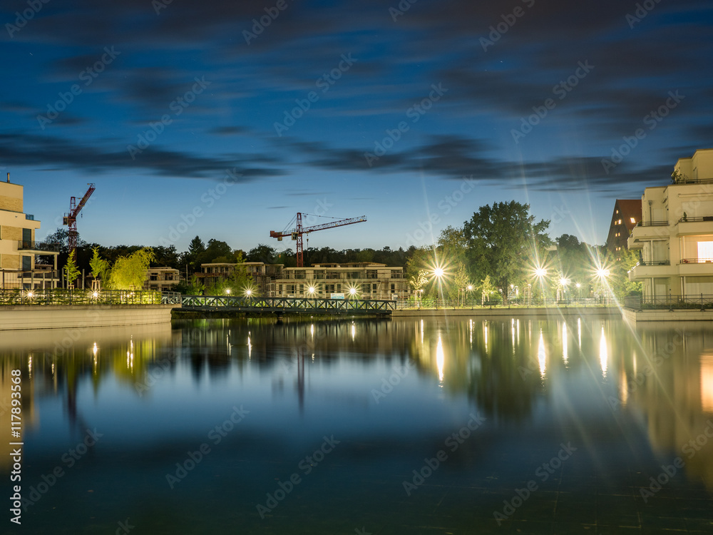 Fototapeta premium construction cranes and apartment buildings around a small lake
