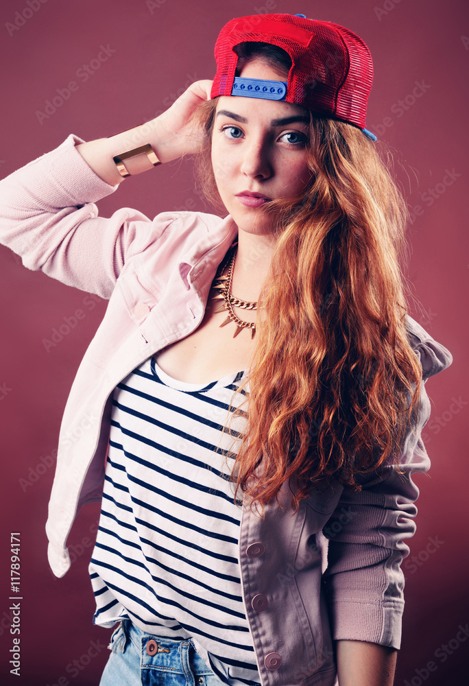 Sexy hip-hop woman in cap with long red hair. Fashion portrait of modern girl in cap Sexy hip-hop woman in cap with long red hair. Fashion portrait of modern girl in cap