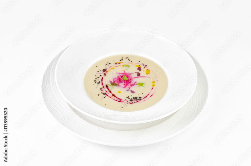 Cream soup of cauliflower with beetroot and truffle oil on a plate on a white background Cream soup of cauliflower with beetroot and truffle oil on a plate on a white background