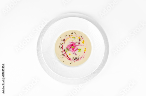 Cream soup of cauliflower with beetroot and truffle oil on a plate on a white background, top view