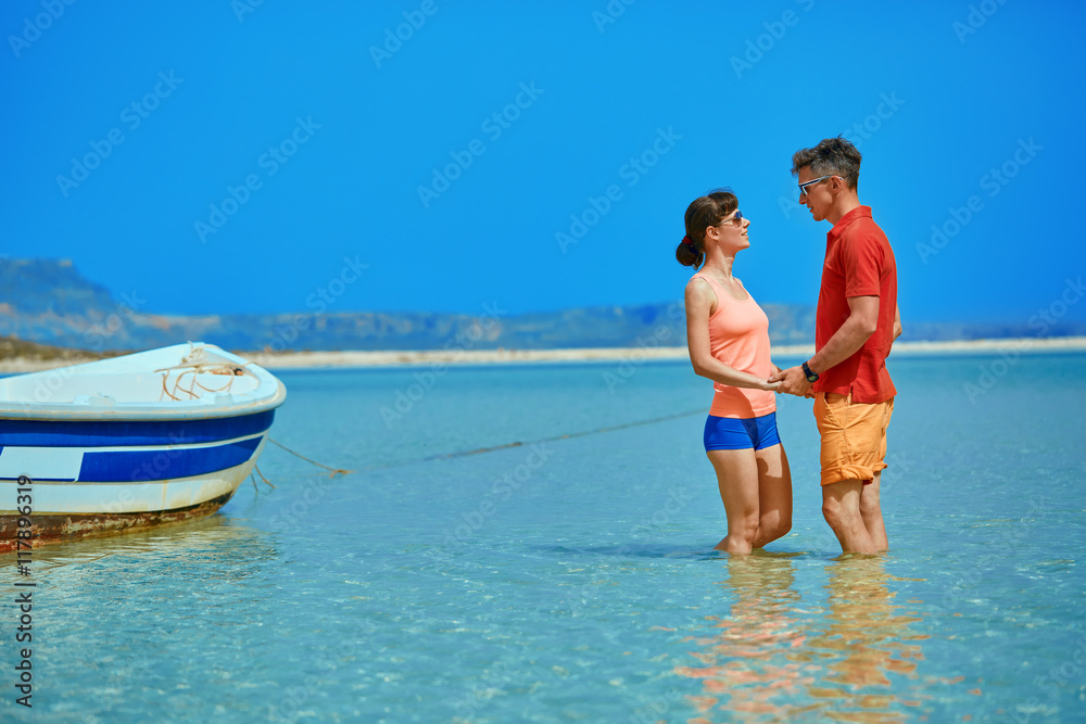 Obraz premium couple standing in the sea near the boat. They hold each other's hands