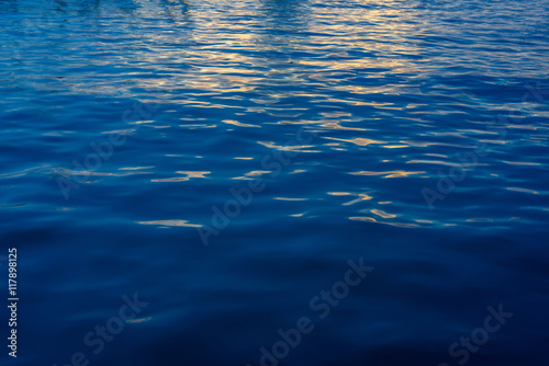 Reflection of yellow light on blue sea ripples