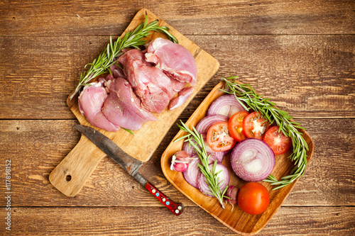 Raw turkey fillet with spices on a wooden background.
