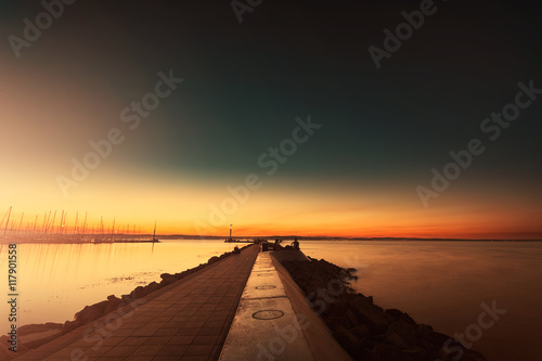 Fototapeta Naklejka Na Ścianę i Meble -  Pier at sunset by the lake Balaton Hungary with fishing people silhouette and mood sunlight