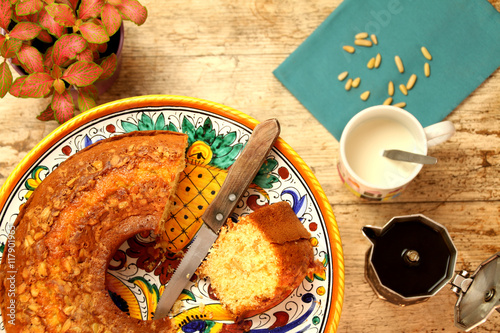 Breakfast with homemade ciambellone, milk, coffee. A plant, a blue napkin and some pine nuts. photo