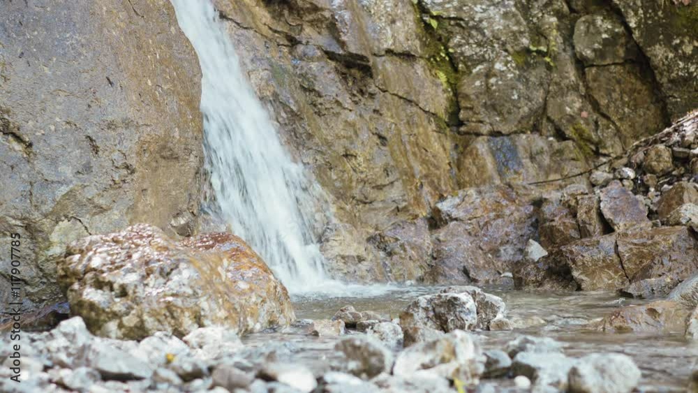 Wasserfall eines Gebirgsbaches mit klarem und reinem Quellwasser in den bayerischen Alpen, eingerahmt von grauen Felsen und Steinen. Wasserfall eines Gebirgsbaches mit klarem und reinem Quellwasser in den bayerischen Alpen, eingerahmt von grauen Felsen und Steinen.