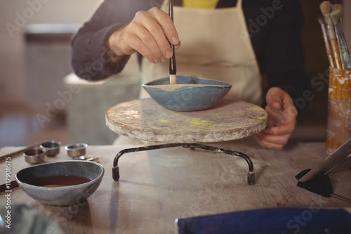Male potter painting on bowl