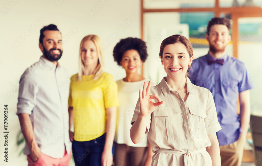 happy woman showing ok over creative office team happy woman showing ok over creative office team