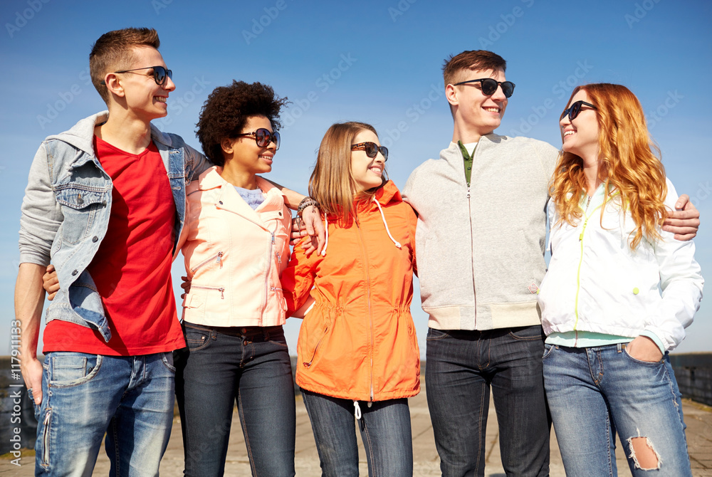 Obraz premium happy teenage friends in shades talking on street