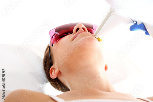 Klinika kosmetyczna, kobieta podczas zabiegu depilacji laserowej twarzy
