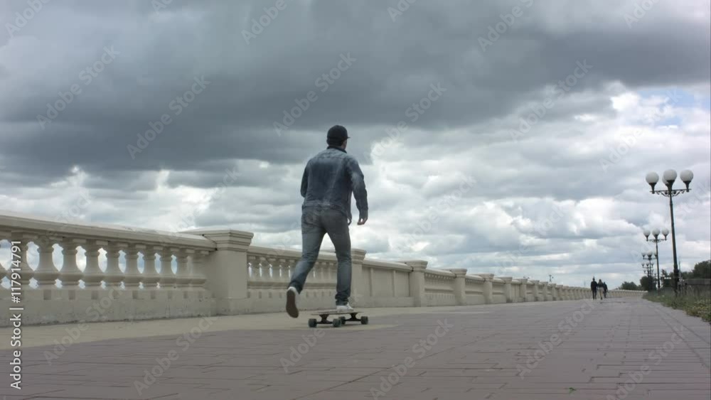 Young man riding a skateboard in cloudy day. Young man riding a skateboard in cloudy day.