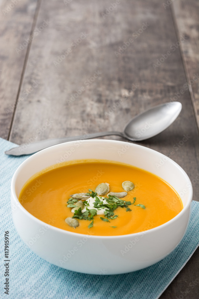 Pumpkin soup and pumpkin seeds on rustic wooden background
Pumpkin soup and pumpkin seeds on rustic wooden background