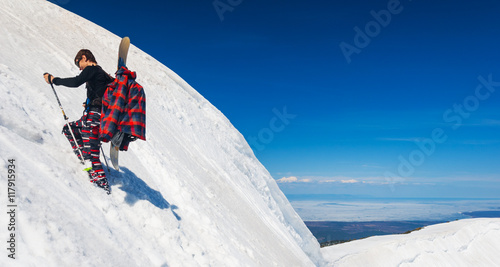 Young snowboarder climbing up the slope