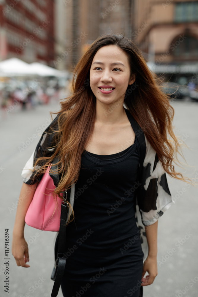 Young Asian woman in city walking smile happy face
