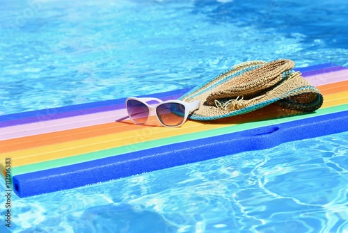 Pool with clean water. Hat, sun glasses on air mattress lilo. Summer background for traveling and vacation.