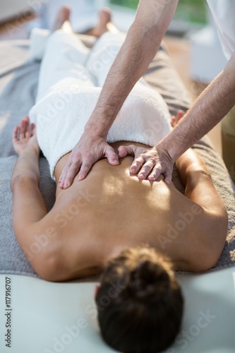 Male physiotherapist giving back massage to female patient