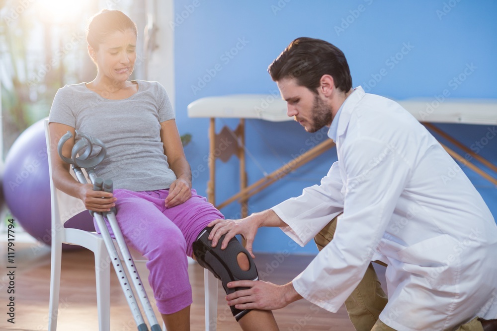 Physiotherapist examining female patients knee Physiotherapist examining female patients knee