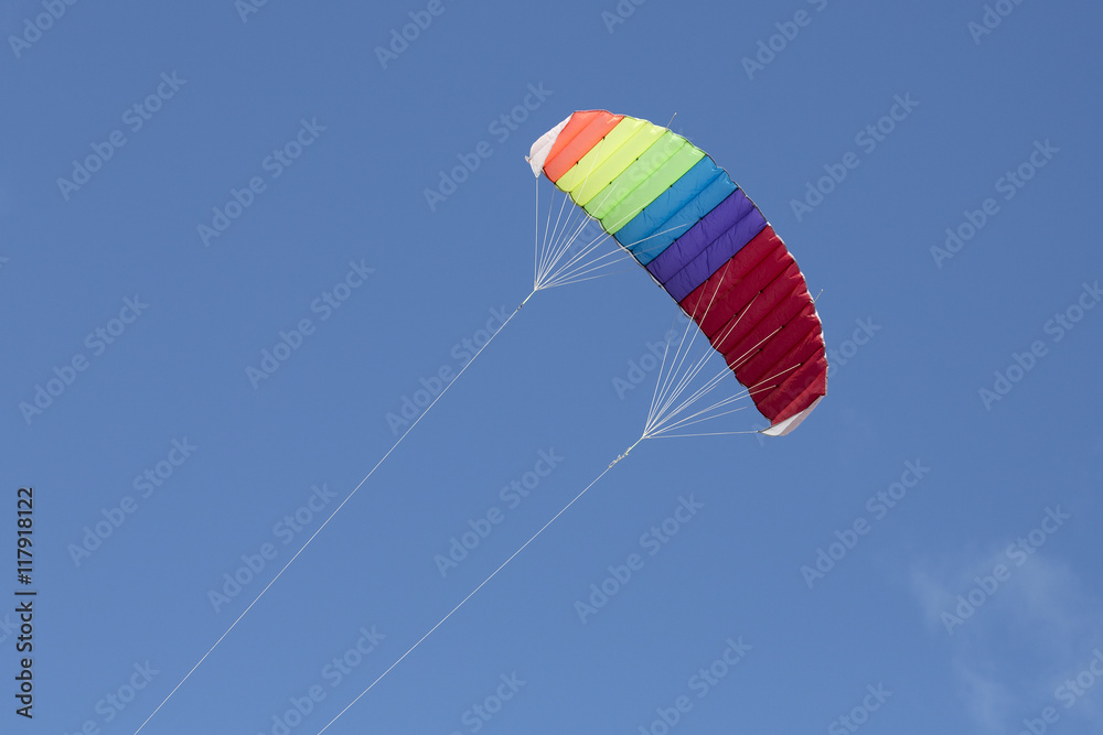 Multi-colored kite flying with a blue sky Multi-colored kite flying with a blue sky