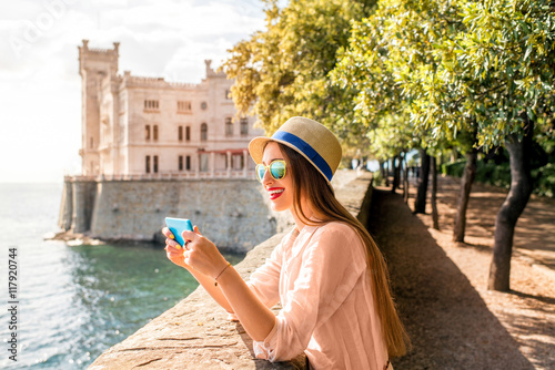 Young woman having fun photographing landscape near Miramare castle in northeastern Italy. Traveling in Italy