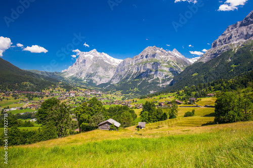 View to famous Grindelwald valley, green forest, Alps chalets and Swiss Alps (Schreckhorn, Berglistock and Wetterhorn) in the background, Berner Oberland, Switzerland, Europe. 