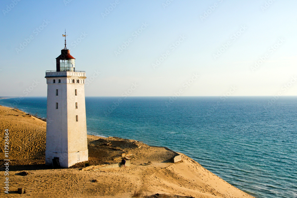 A lonely abandoned lighthouse waiting for the sea to come and for its fall in the sea. 