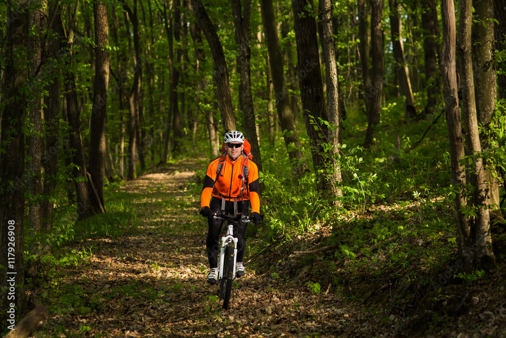 Biker in orange jersey on the forest road