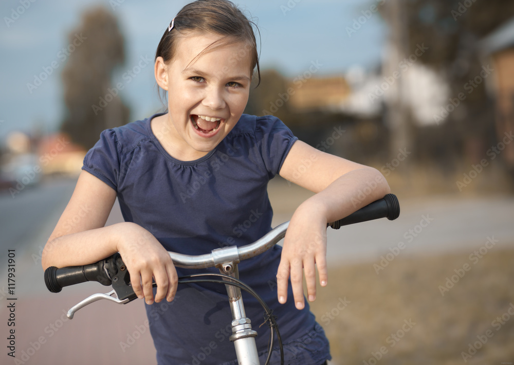 Obraz premium Cute girl is sitting on bicycle