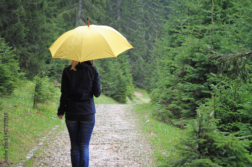 Happy Woman with yellow umbrella walking in forest under the rain. Happiness, positivity concept