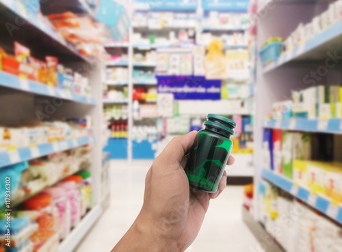 Hand with plastic pill bottle on pharmacy store