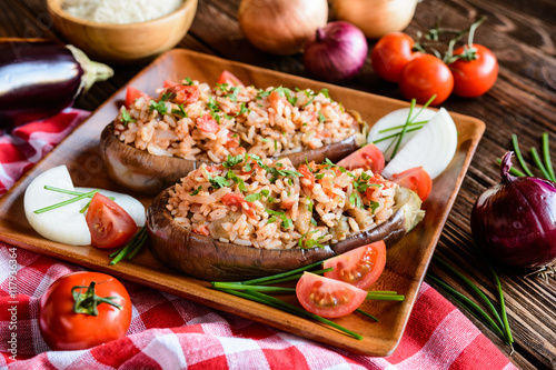 Baked stuffed eggplant with rice, tomato and onion on a wooden plate