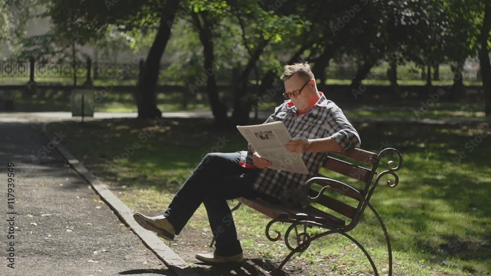 A man with glasses walks on the city pond embankment, holding his hat. Walk into a bright warm Sunny day. A man with glasses walks on the city pond embankment, holding his hat. Walk into a bright warm Sunny day.