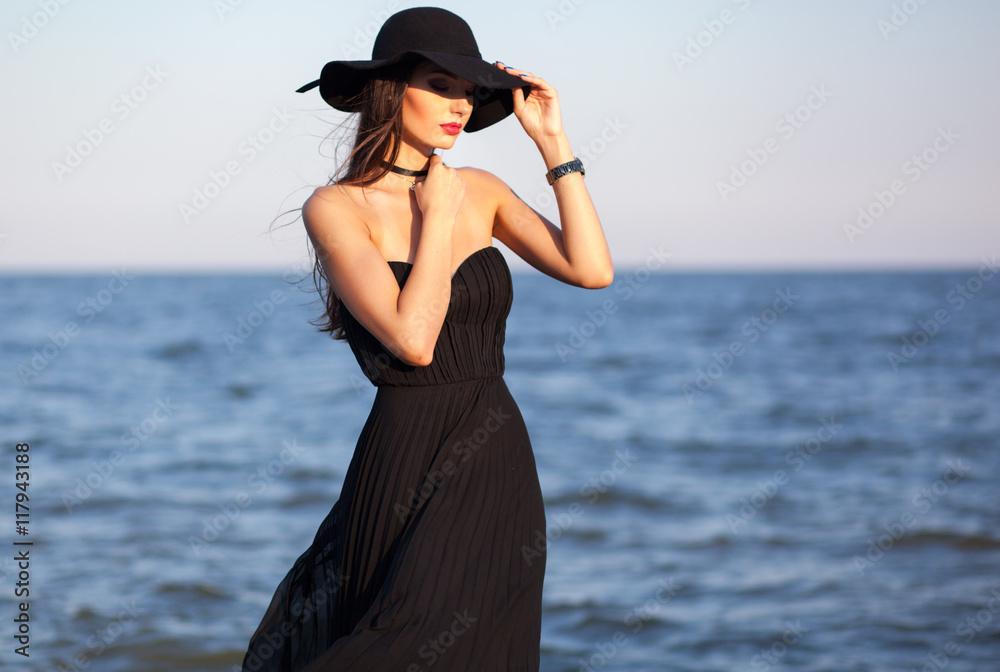 Beautiful elegant lady in hat and long bkack dress at the seasi Beautiful elegant lady in hat and long bkack dress at the seasi