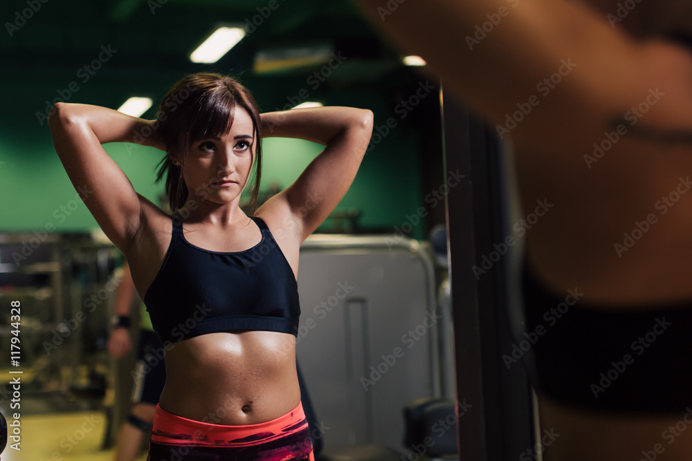 Young woman at the gym getting ready for exercising in front of a mirror
