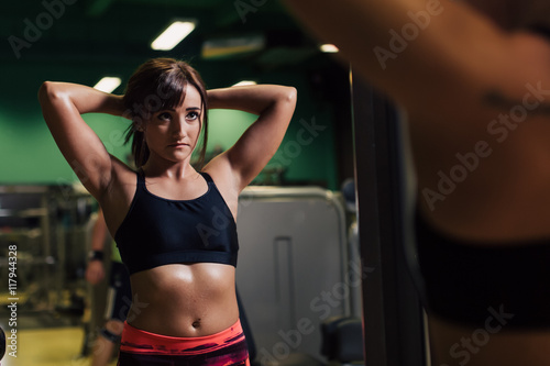 Young woman at the gym getting ready for exercising in front of a mirror   © chrisgraphics