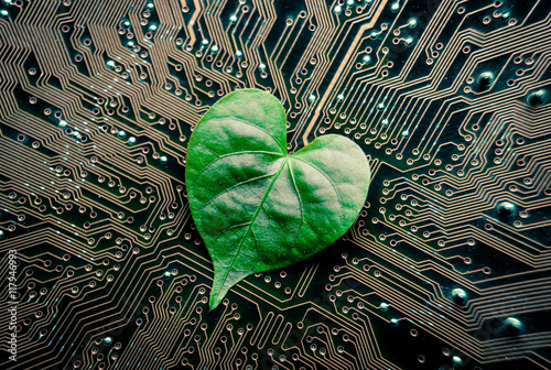 A green leaf with a heart shape on a computer circuit board / green it / green computing / csr / it ethics
