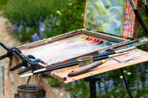 Painter's Palette and Easel Outdoors with Oil Landscape of Surrounding Wildflowers in Mountains