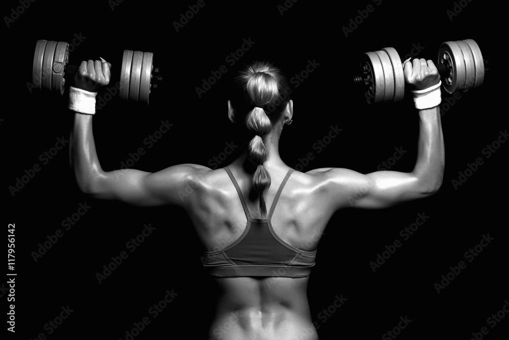 monochromatic bodybuilder young woman with dumbbells.blonde girl with muscles.gym