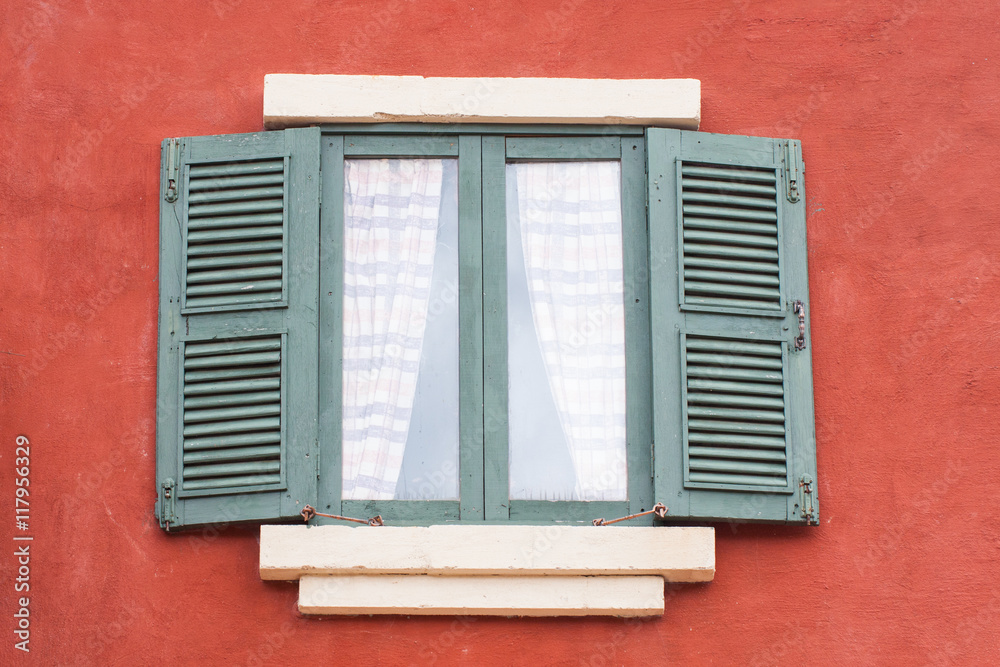 Decorative old window on an old red stucco wall 