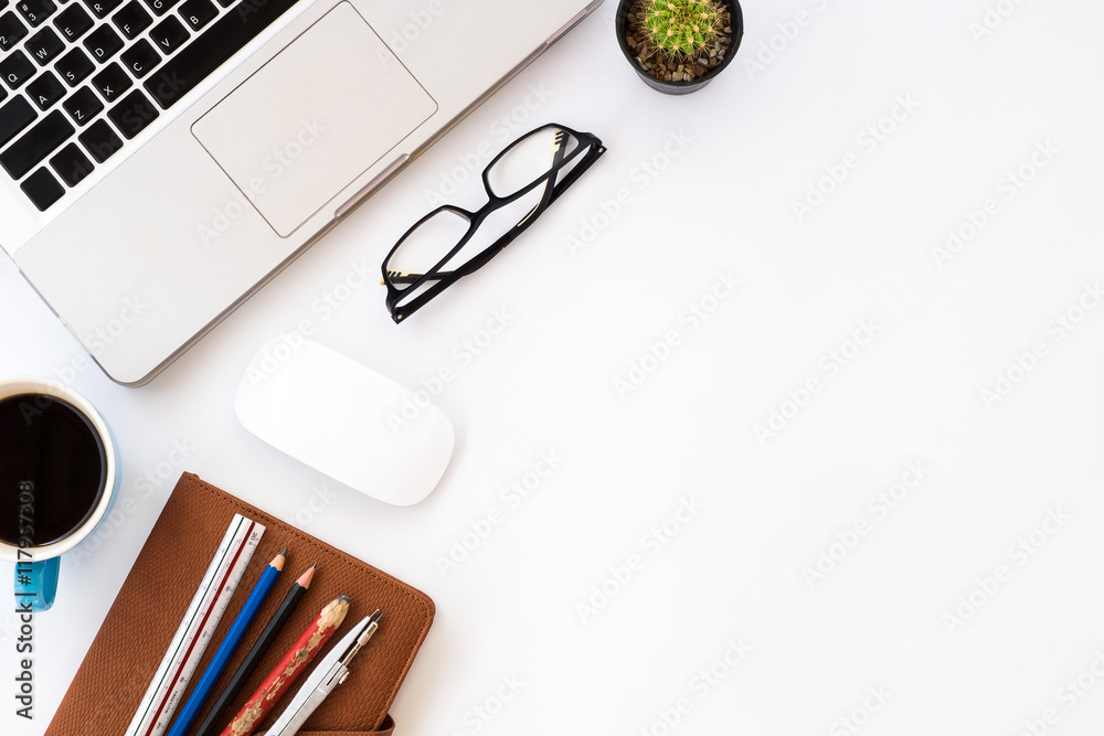 White office desk table with pencils, laptop, eyeglasses, leather notebook, mouse and cup of coffee. Top view with copy space White office desk table with pencils, laptop, eyeglasses, leather notebook, mouse and cup of coffee. Top view with copy space