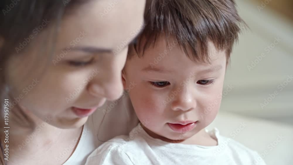 Young mother sitting with her little son and telling him about something Young mother sitting with her little son and telling him about something