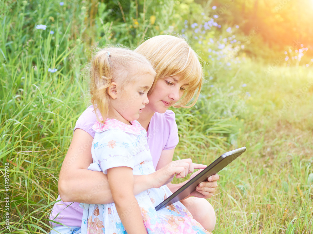 Happiness mom and daughter web surfing using tablet outdoors on Happiness mom and daughter web surfing using tablet outdoors on