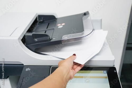 businesswoman pull pieces of paper from the printer