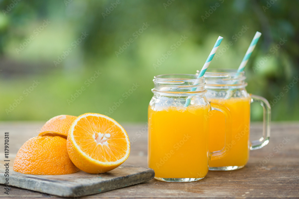 Fresh orange juice and orange sliced ripe on wooden table. Green background. Fresh orange juice and orange sliced ripe on wooden table. Green background.