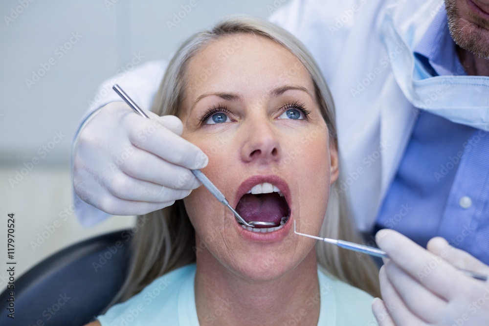 Dentist examining a woman with tools Dentist examining a woman with tools
