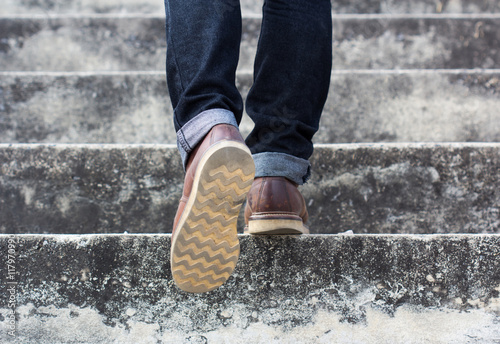 a man with blue geans and  sneaker shoes in stair