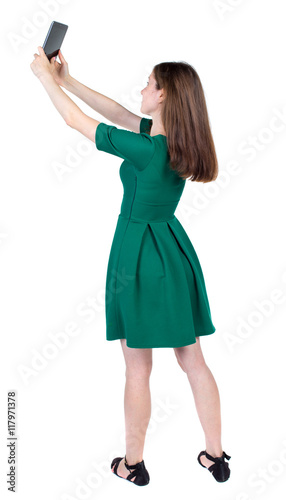 back view of standing young beautiful  woman  using a mobile phone. girl  watching. Rear view people collection.  backside view of person.  Isolated over white background. The slender brunette in a © ghoststone