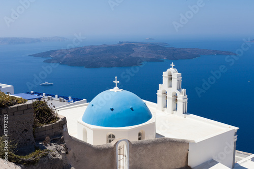 The Three bells of Fira and blue dome, Santorini, Greece with Santorini's volcano in the background