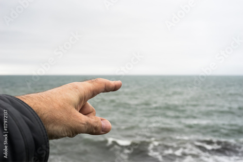 Zeigefinger zeigt auf das Meer - Forefinger pointing to the sea photo