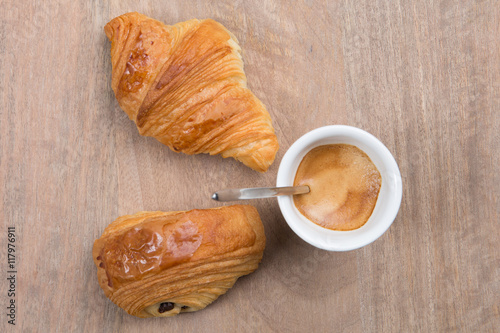 Croissants and coffee on a wooden table background.