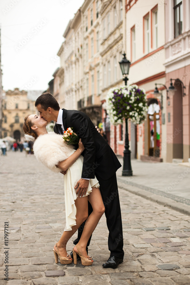 Groom kisses passionately a bride in short dress